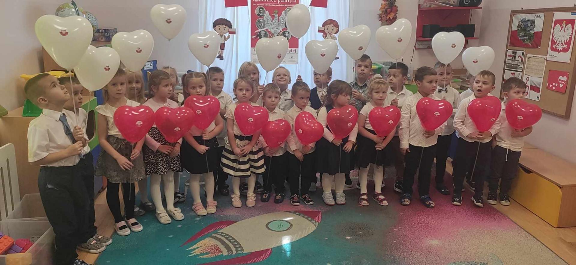 Na zdjęciu znajdują się dzieci trzymające balony w kolorach biało-czerwonych 